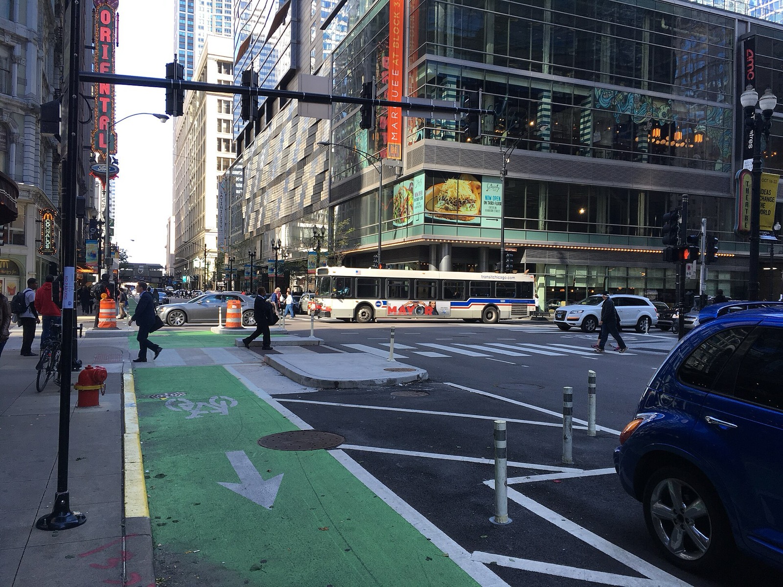 A green protected bike lane with bollards at a downtown Chicago intersection