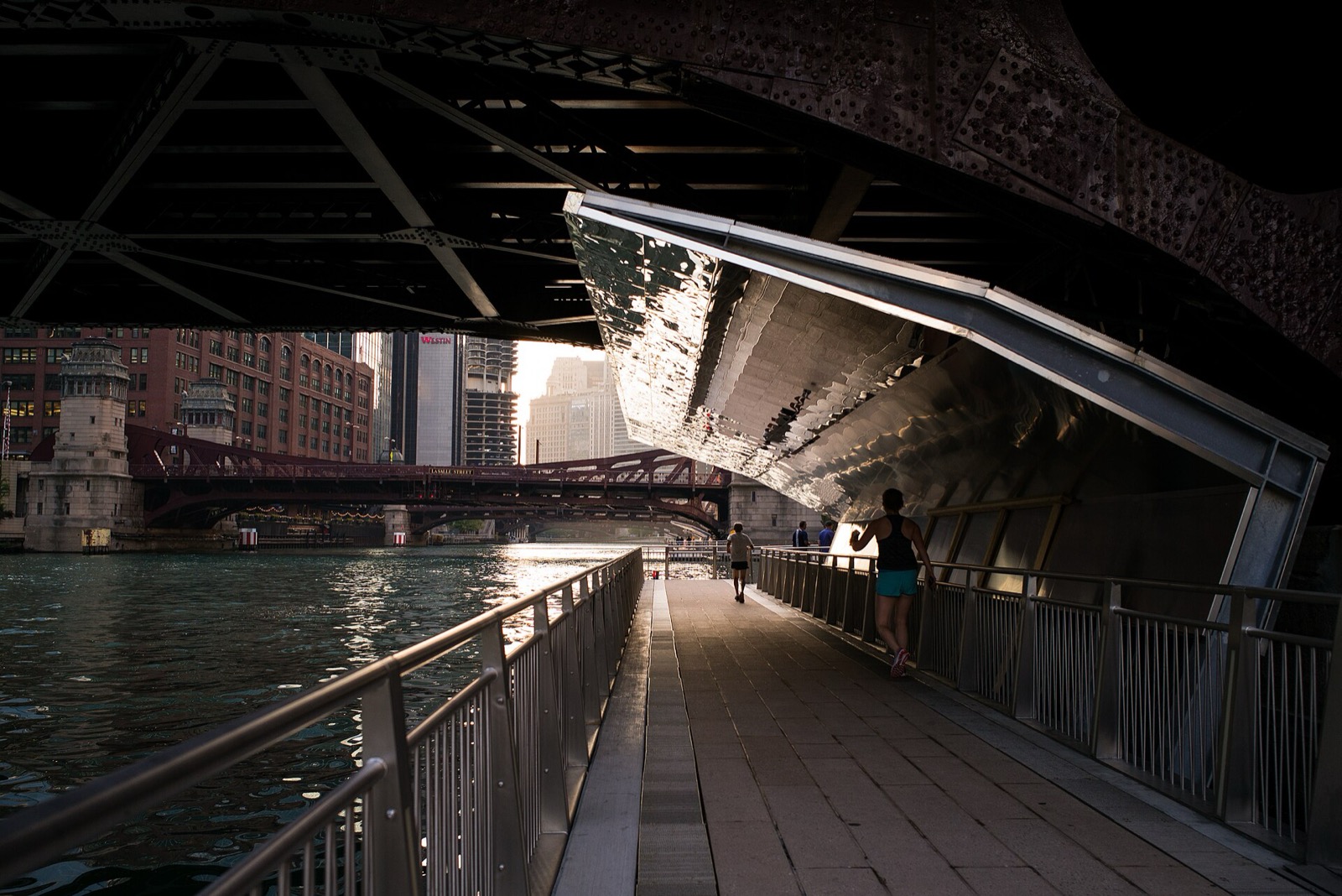 The Chicago Riverwalk passing under a bridge beside the river